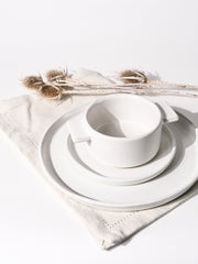 The image features a white cup placed on a plate.