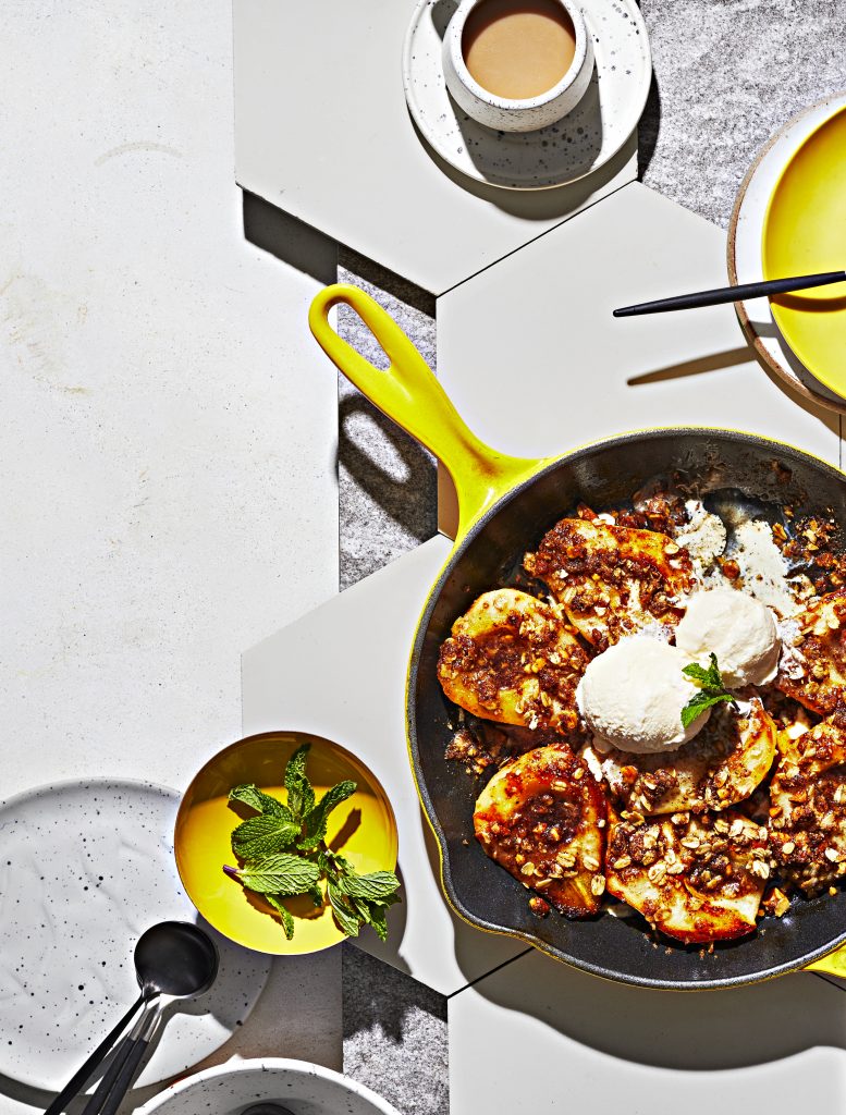 Overhead shot of skillet honey-roasted pears with brown sugar crumble and ice cream, exuding warm, inviting flavors.
