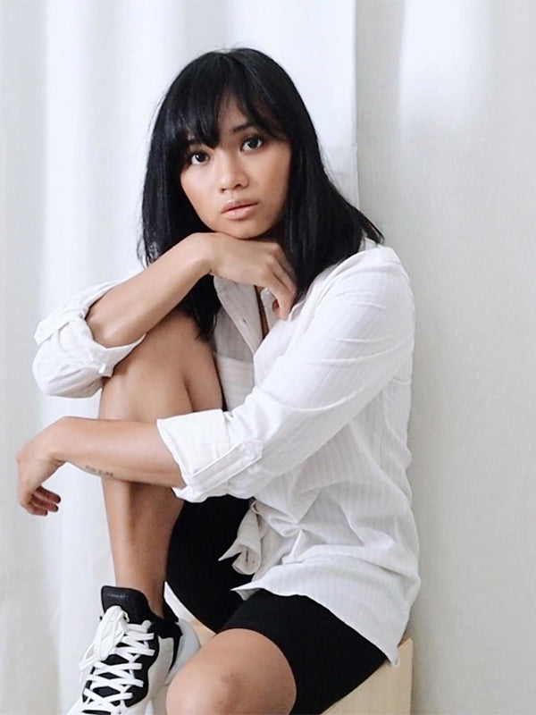 Portrait of a serene woman in a white shirt and sneakers, reflecting on her journey to sobriety and self-discovery.