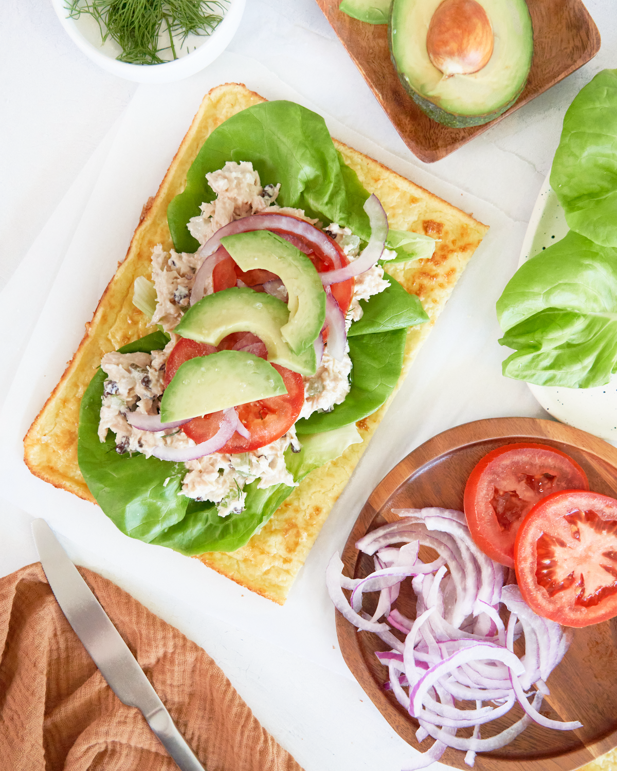 Overhead shot of a tasty chicken salad wrap with avocado, tomato, and lettuce on a light and airy cottage cheese "bread." 
