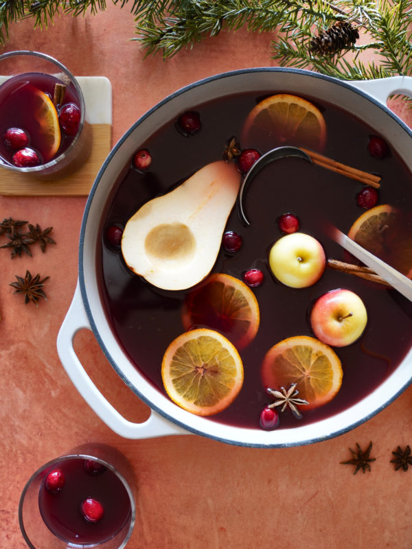 Festive mulled wine simmering in a large pot, garnished with fruit and spices. Warm, inviting, and perfect for a cozy gathering.
