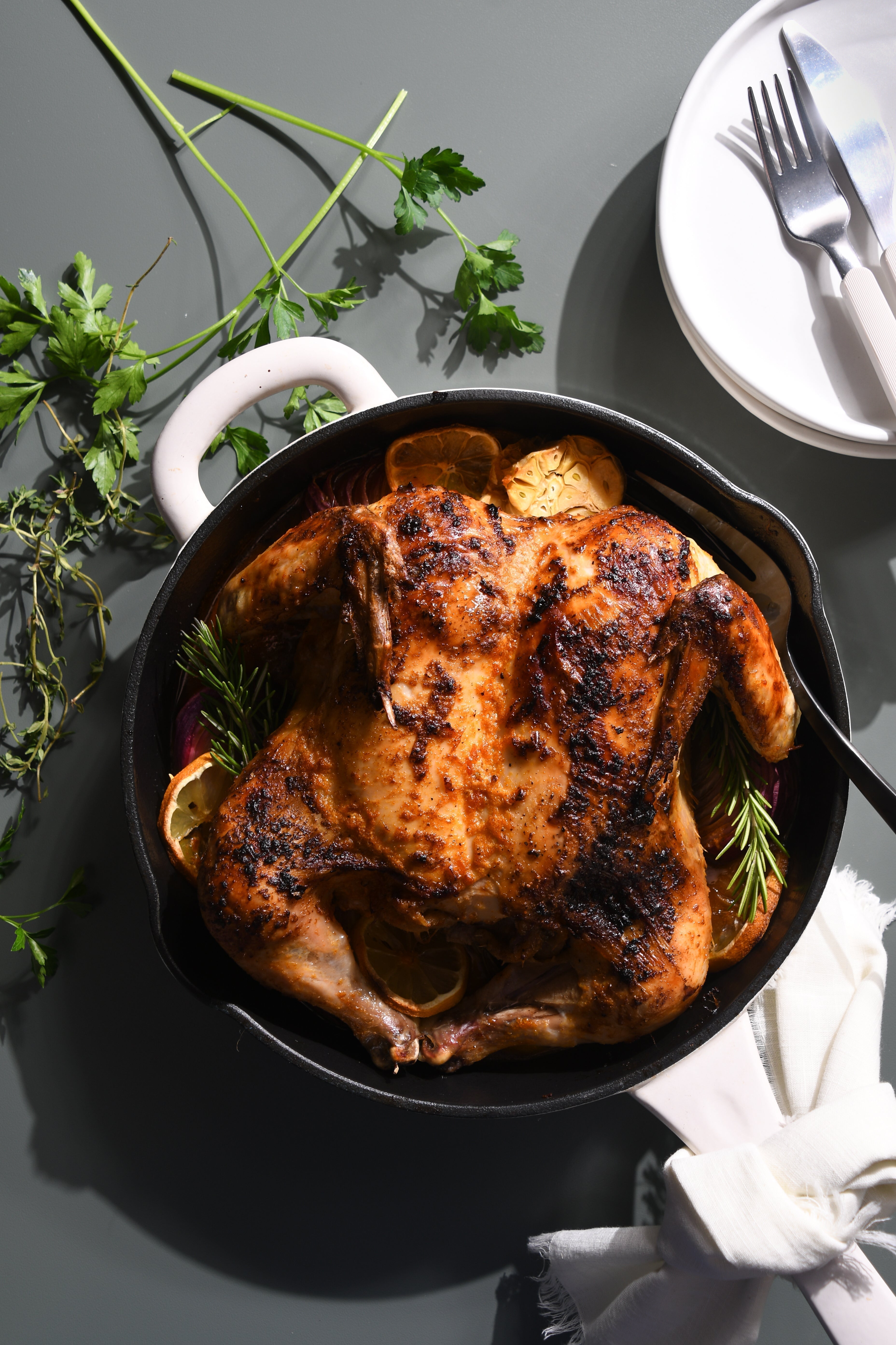 Overhead shot of a vibrant, roasted spatchcock chicken in a cast iron skillet with herbs, conveying a sense of deliciousness.