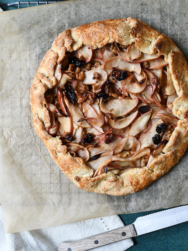 Rustic apple galette with walnuts and dried cherries, capturing the warmth of autumn baking. A delightful, inviting treat.
