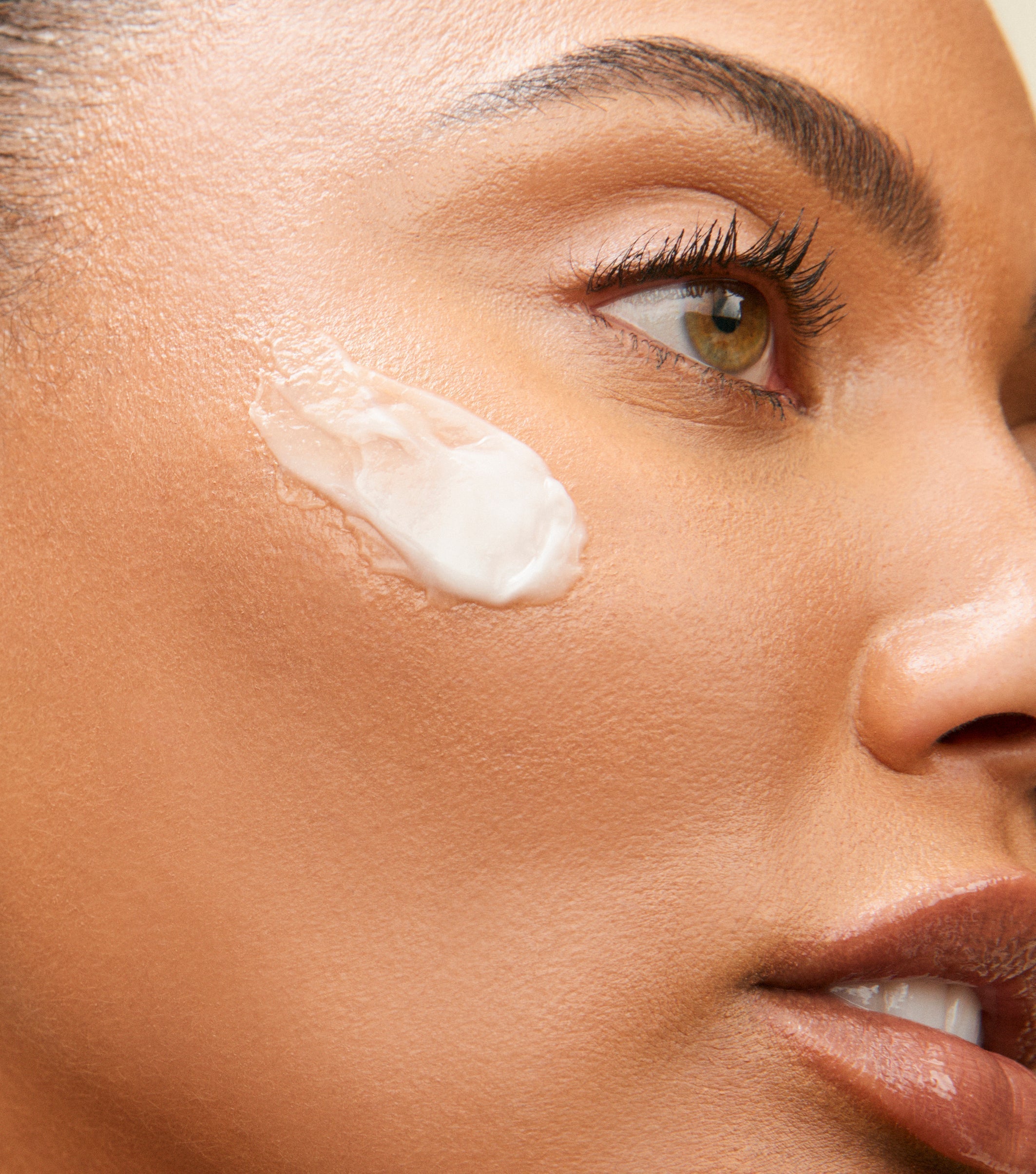 Close-up of a woman applying moisturizer to her face, emphasizing skincare routine and hydration. 
