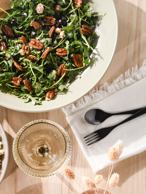 Overhead shot of an arugula salad with pecans and balsamic dressing, conveying a fresh, healthy, and appetizing mood.