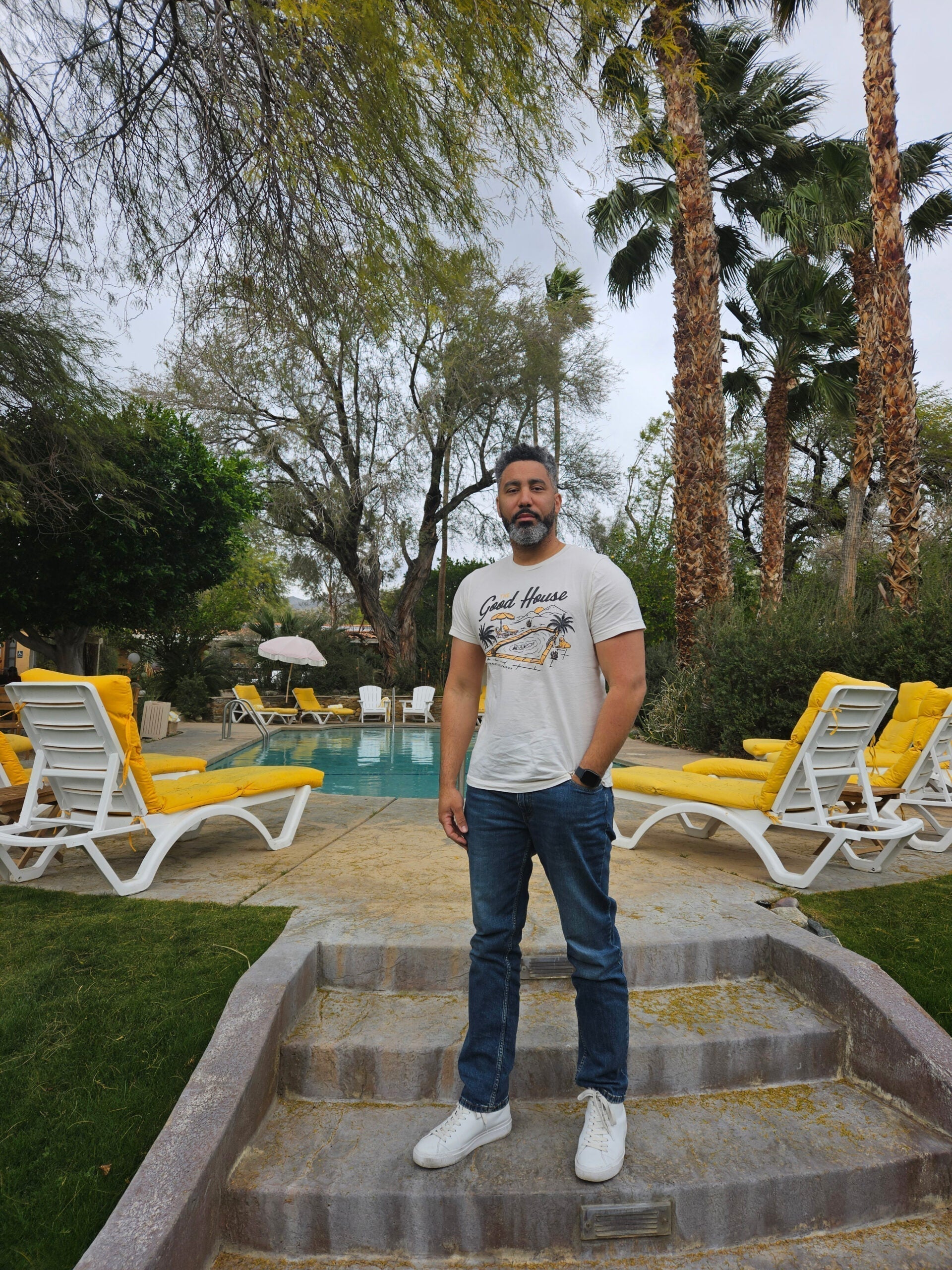A confident Black entrepreneur stands by a Palm Springs pool, embodying the relaxed yet powerful spirit of the Coachella Valley's cultural shift.
