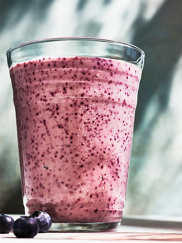 A refreshing blueberry smoothie in a clear glass, showcasing its vibrant purple hue and fresh ingredients. A tasty and healthy drink.
