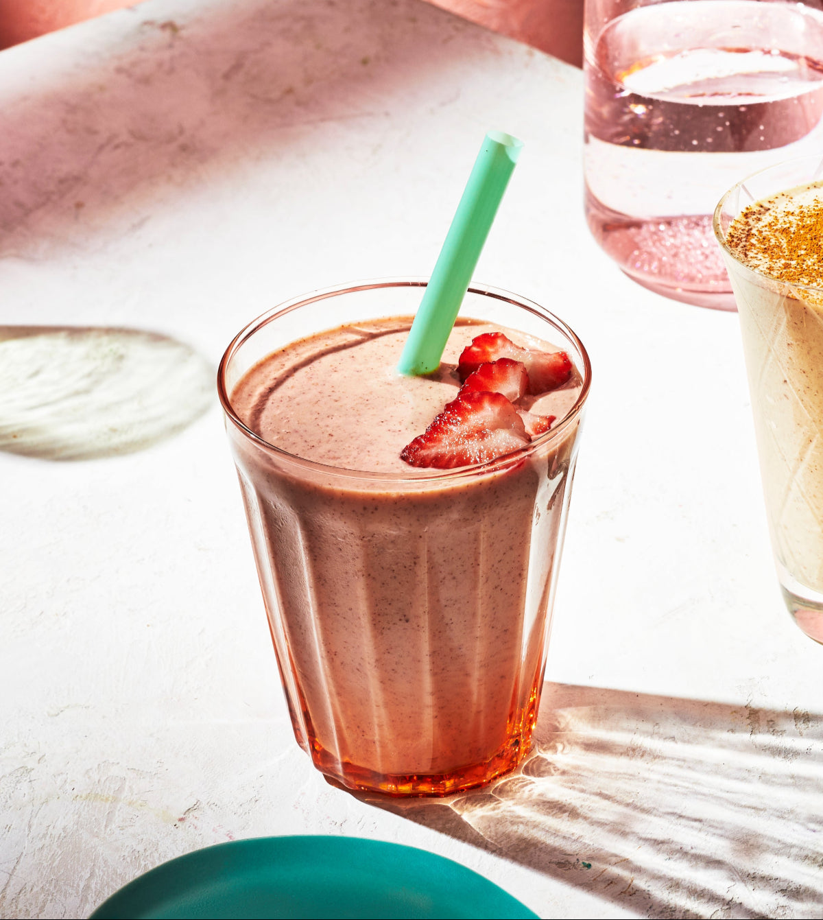 Inviting image of a strawberry smoothie in a faceted glass, topped with fresh berries and a green straw.