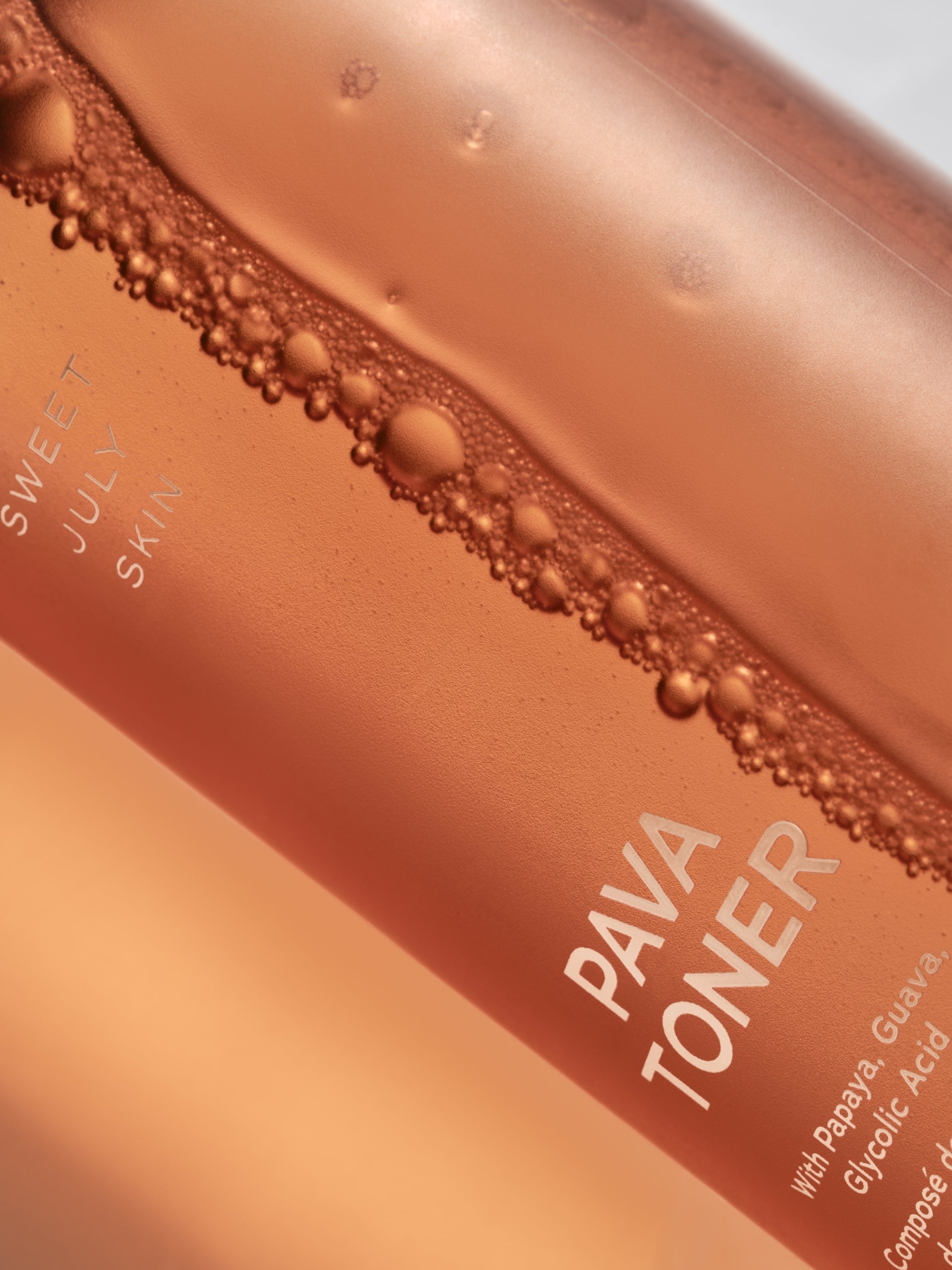 Rose-colored Pava Toner by Sweet July Skin, showing bubbles along the top edge of the bottle.