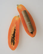 Tan cream tube by Sweet July Skin placed on a halved papaya.