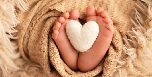 The image shows a close-up of a baby's feet resting on a blanket. The baby appears to be sleeping peacefully.