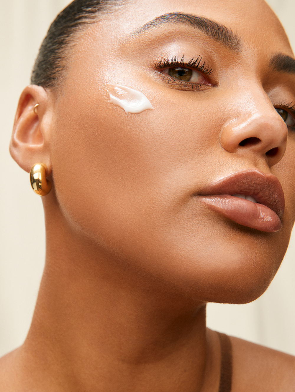 Daily moisturizer cream with a smear on tanned skin.