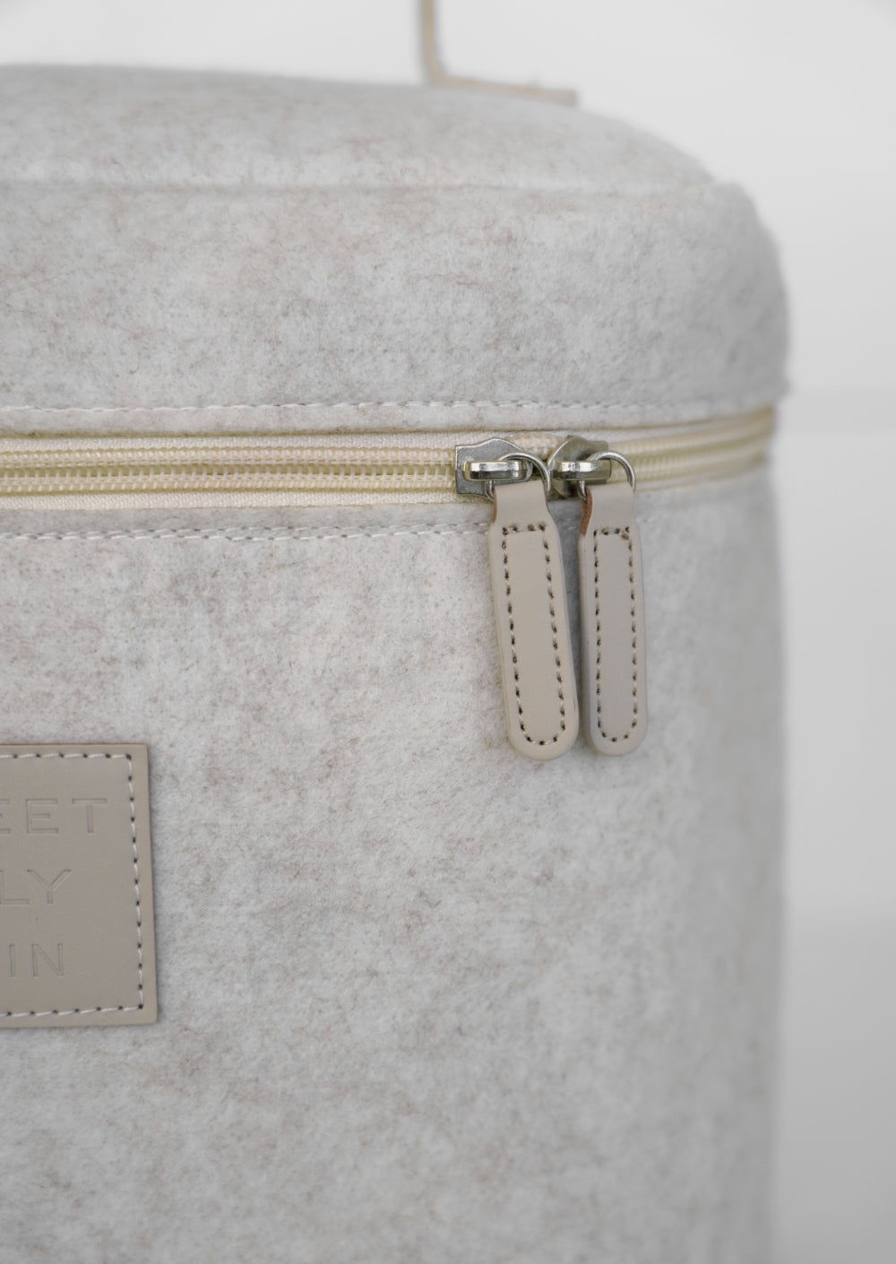 Beige vanity bag by Sweet July Skin, featuring a cream-colored zipper and a felt-like texture.