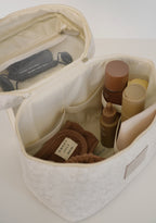 White vanity bag by Sweet July Skin x SortJoy with cosmetics inside and a mesh pocket on the top flap.