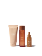 Skincare set by Sweet July Skin, including a cleanser, toner, and face oil, in brown packaging.