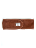 Brown terrycloth headband with a small tag by Sweet July Skin, shown flat on a white background.