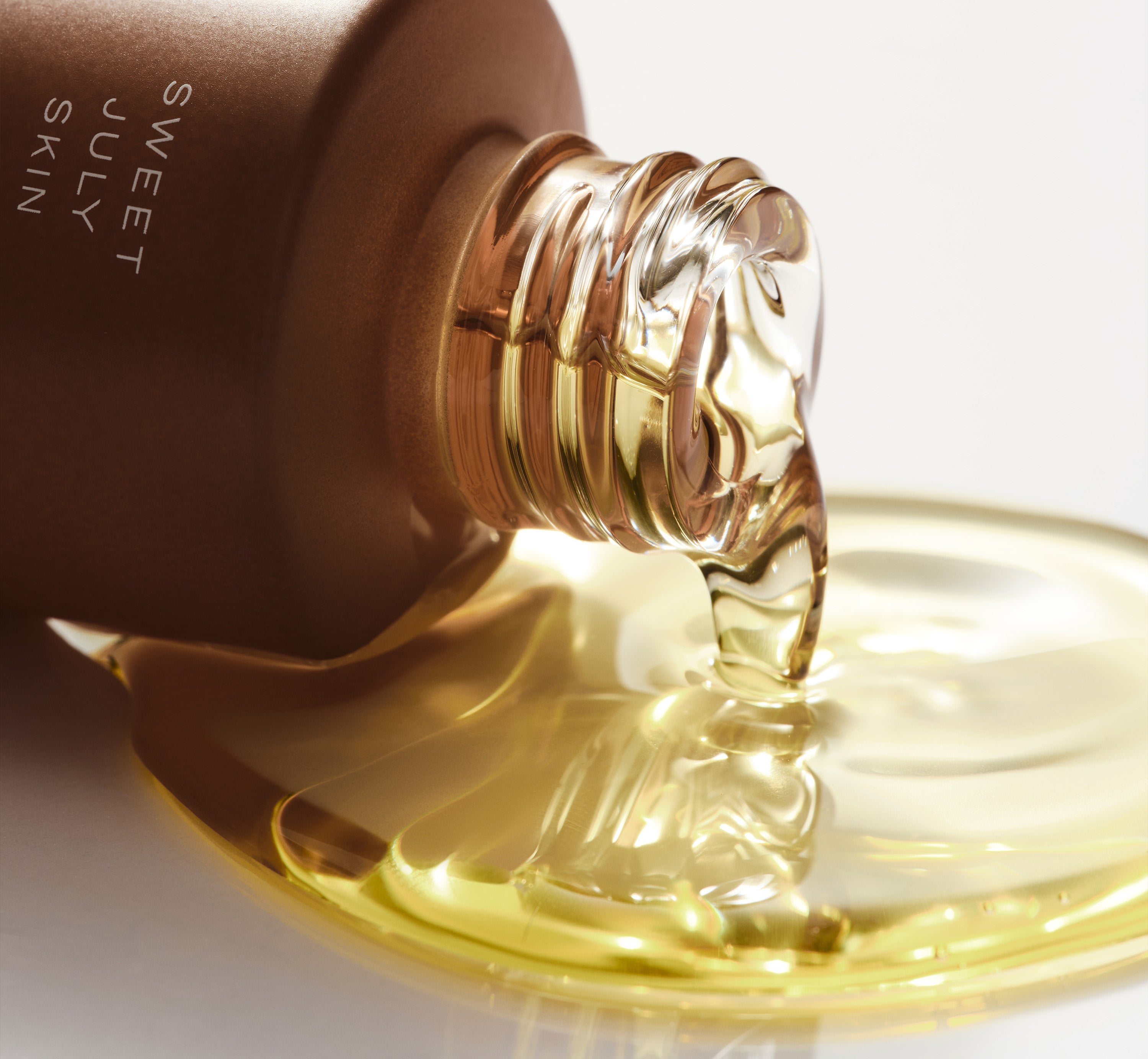 Sweet July Skin Irie Power Face Oil pouring from glass bottle highlighting nourishing skincare oil texture. 