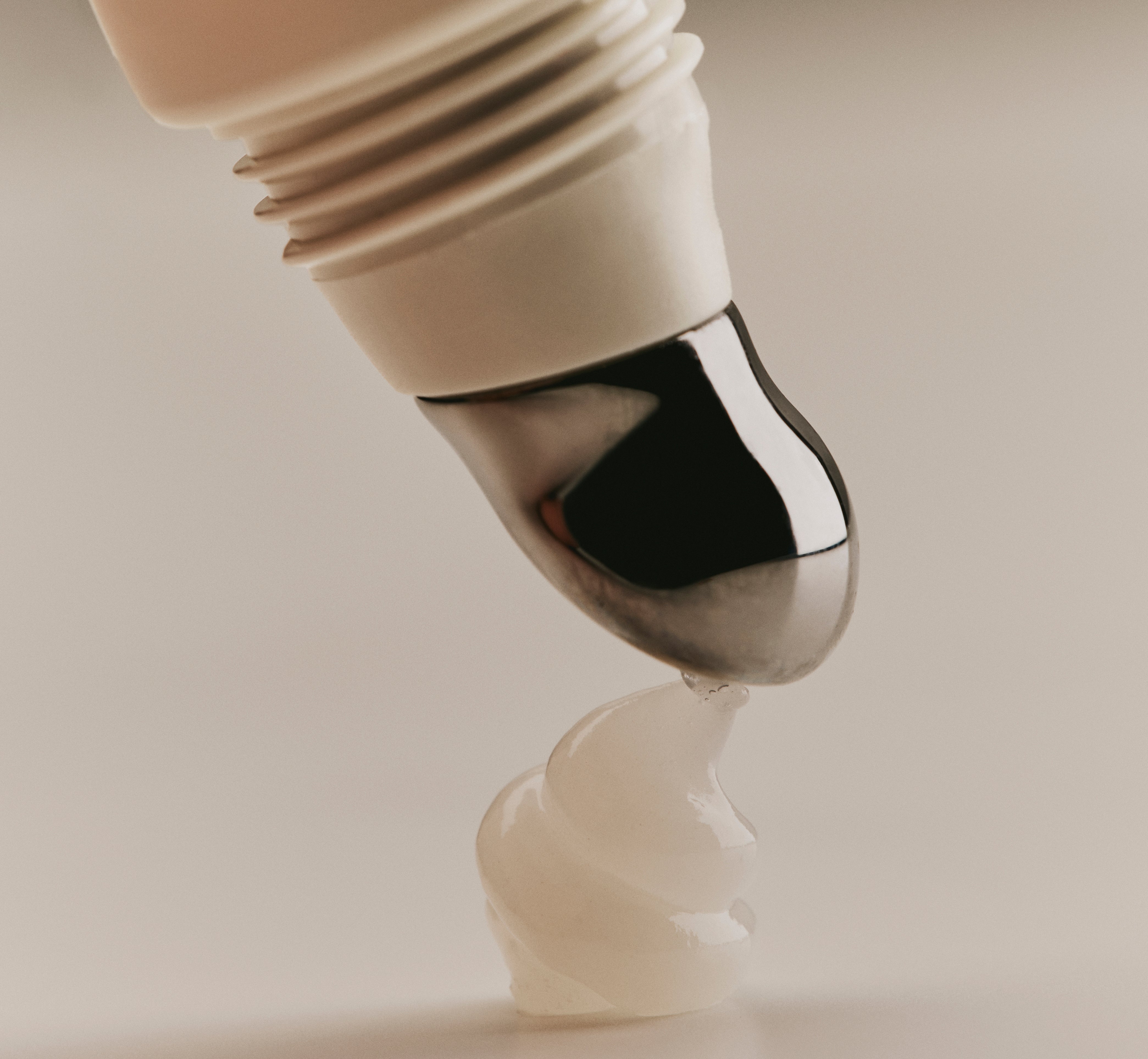 Close-up of Sweet July Lip Treatment in Lychee Jelly dispensing a swirl of translucent product from its silver applicator onto a surface.