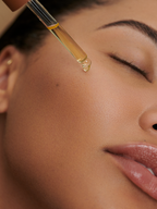 Face oil being applied to skin, with golden hue.