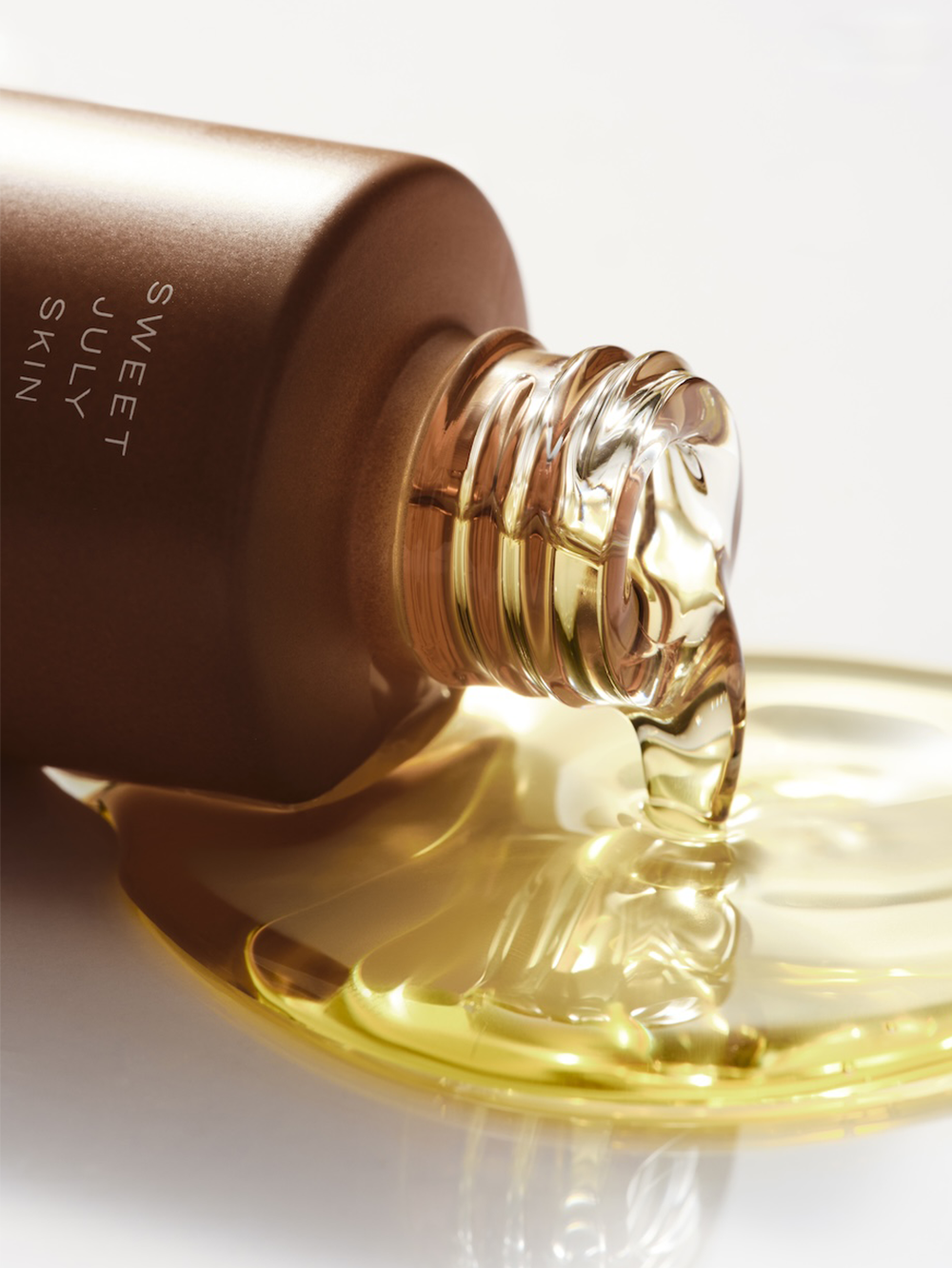 Hydrating face oil by Sweet July Skin being poured onto a white surface.
