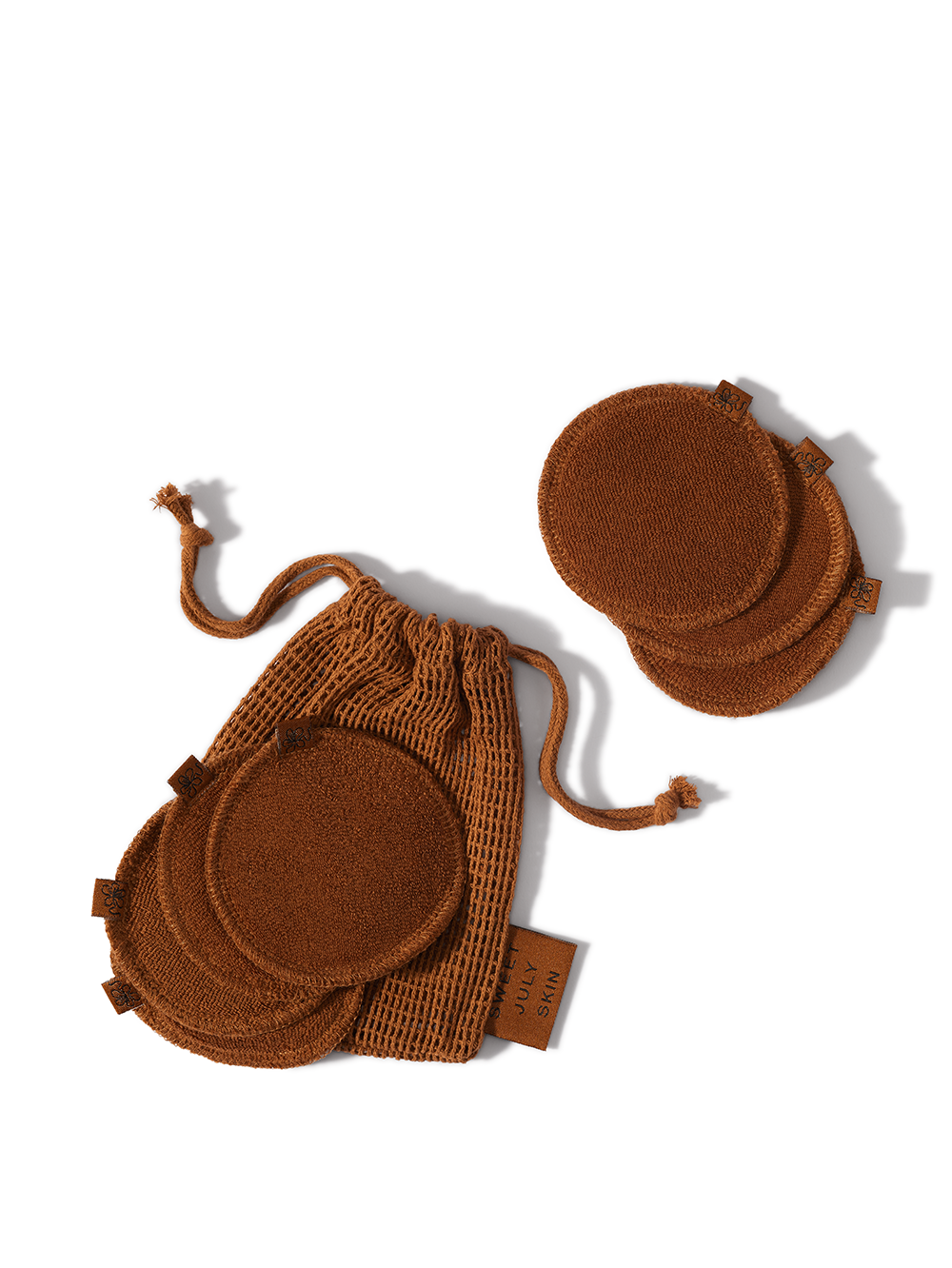 Brown reusable face rounds by Sweet July Skin inside and next to a brown drawstring bag.