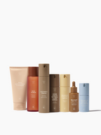 Skincare product set by Sweet July Skin with multiple bottles and tubes in varying neutral colors.
