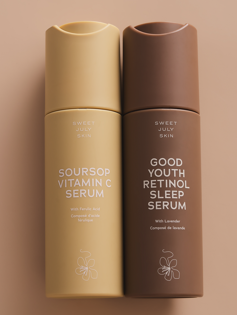 Two skincare serum bottles by Sweet July Skin, one tan and one brown, with flower design at the bottom.
