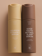 Two skincare serum bottles by Sweet July Skin, one tan and one brown, with flower design at the bottom.
