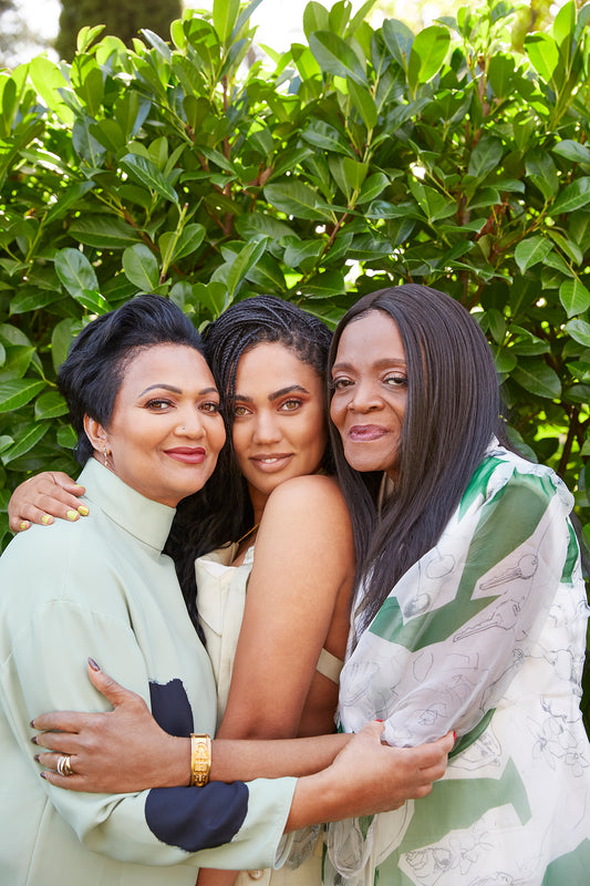 The image shows a group of women embracing outdoors. They appear happy and are dressed in wedding attire. It conveys a sense of friendship and love.