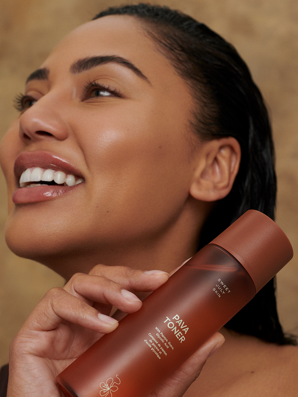 Bottle of face toner by Sweet July Skin held by a woman with wet hair.