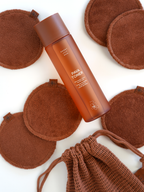 Brown pava toner by Sweet July Skin surrounded by brown reusable cotton rounds and drawstring bag.
