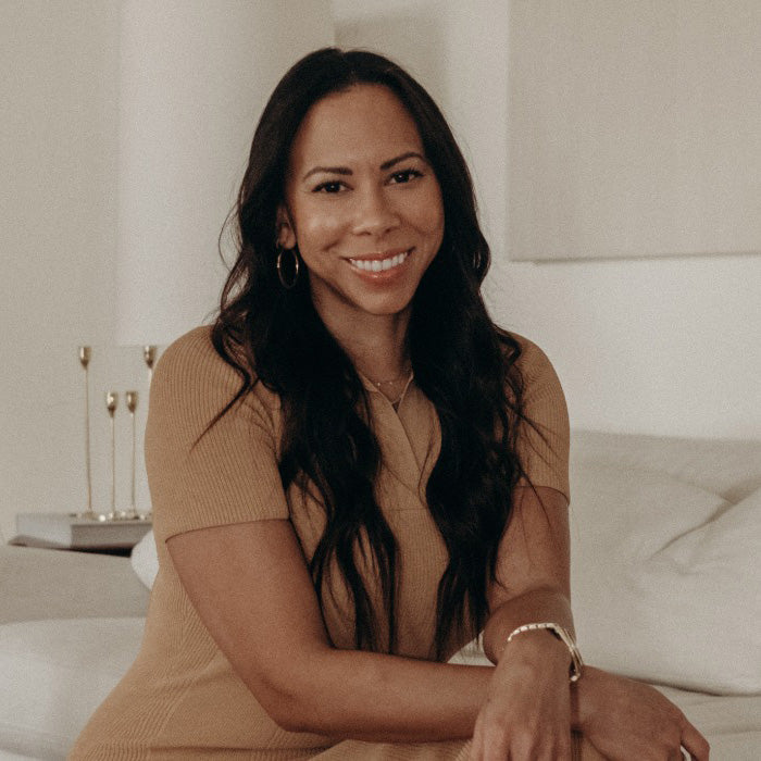 The image shows a woman sitting on a couch indoors, smiling.