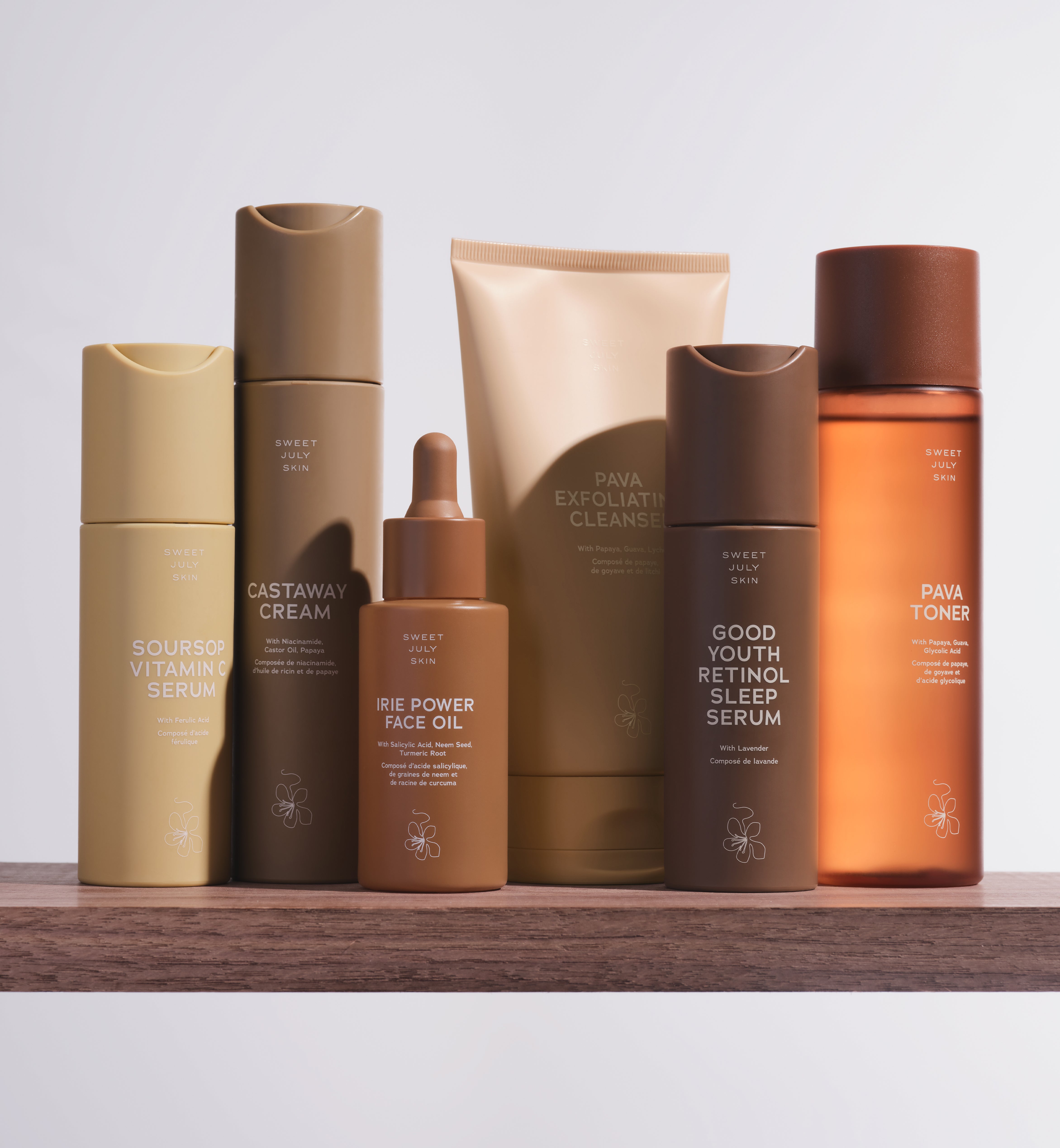 Soursop Serum, Castaway Cream, Irie Power Face Oil, Pava Cleanser, Good Youth Serum and Pava Toner on a wood shelf.