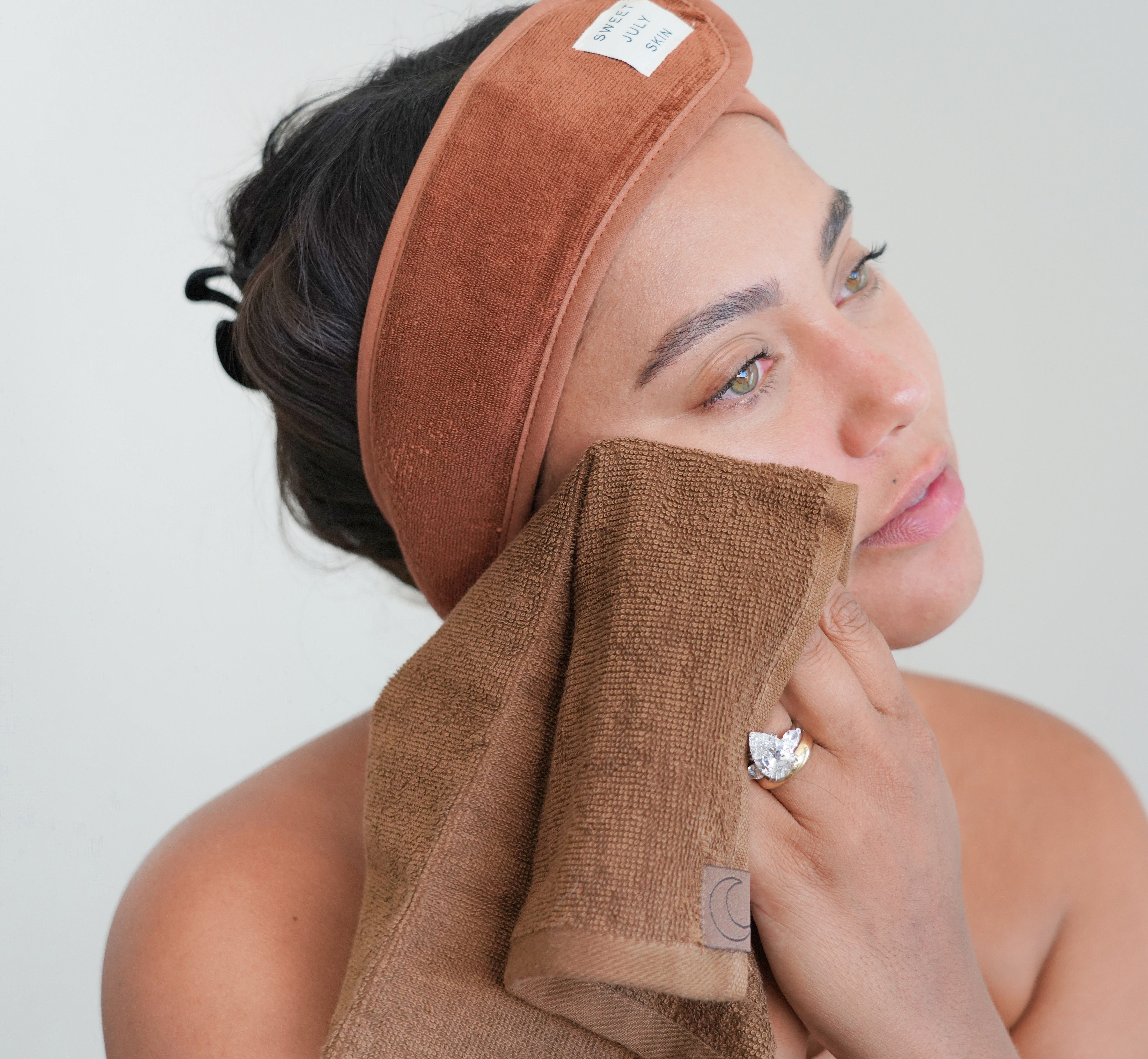 Sweet July founder Ayesha Curry wearing a Sweet July Terry Headband and patting her face with a towel from Day + Night Face Towel Set.