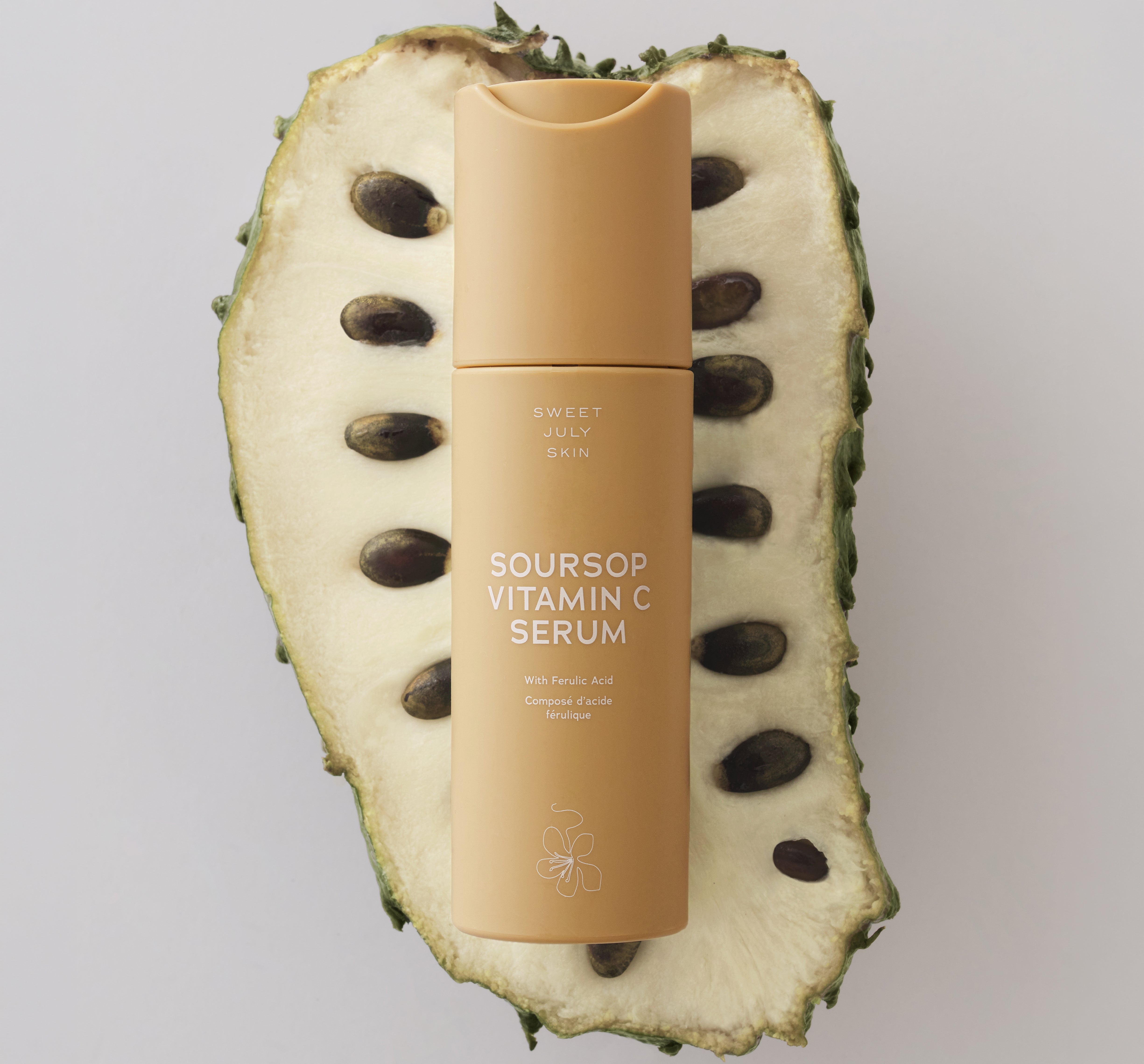 Sweet July Skin's Soursop Vitamin C Serum laying atop a sliced open soursop fruit