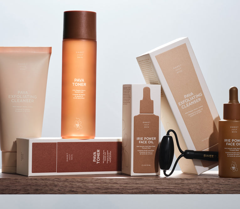 Still life of Sweet July Skin skincare products in neutral tones arranged on a wooden shelf against a bright background.
